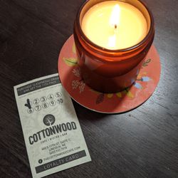 a paper loyalty card for Cottonwood at 440 S 11th St in Lincoln, and a lit candle
