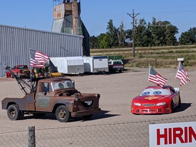 two real-life cars that are made to look like Mater and Lightning McQueen from the Cars movie using big emotive facial features